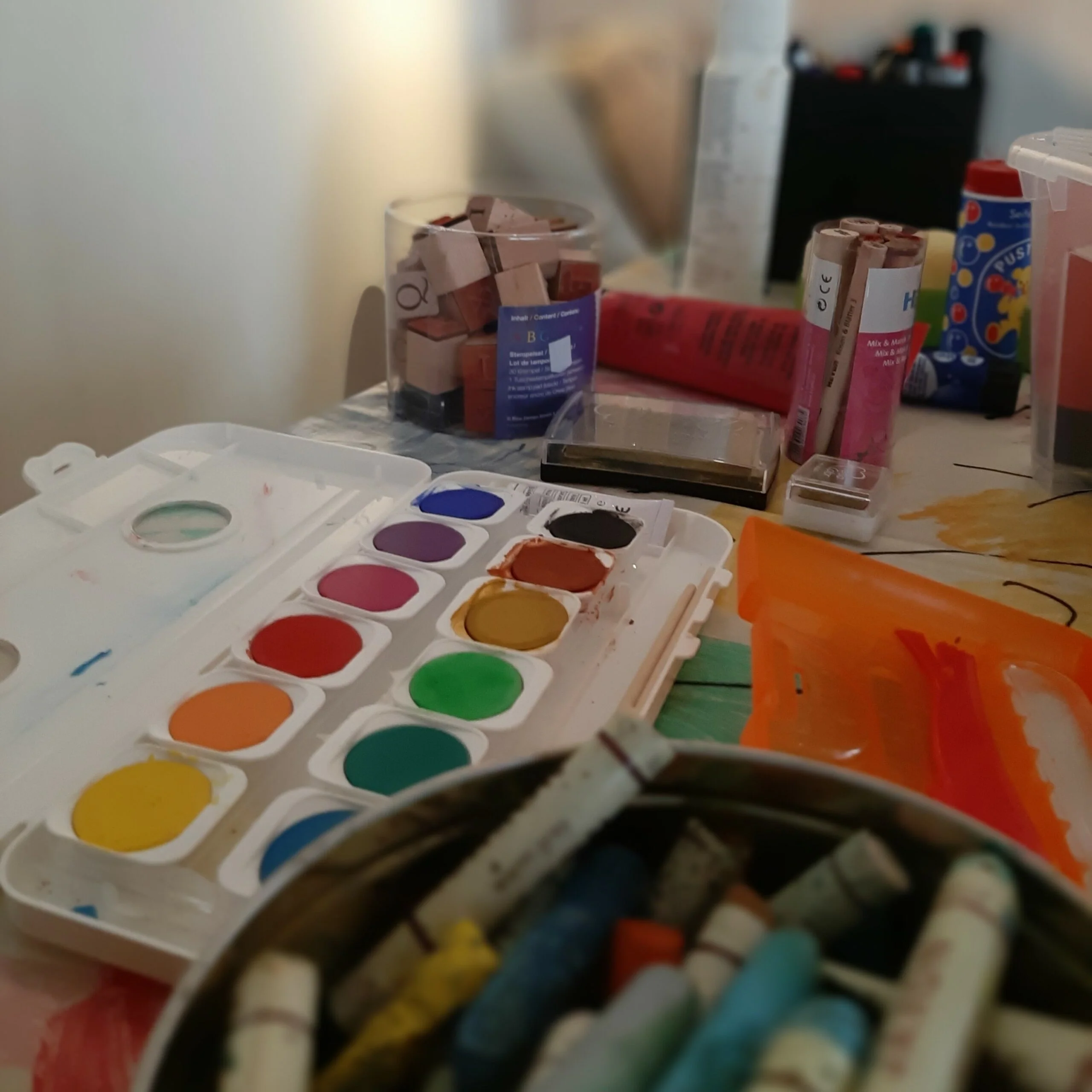 gedenkbretter-gestalten-farbpalette-workshop Bunte Farbpalette, Pinsel und Farbtuben liegen auf einem Tisch zum kreativen Gestalten.